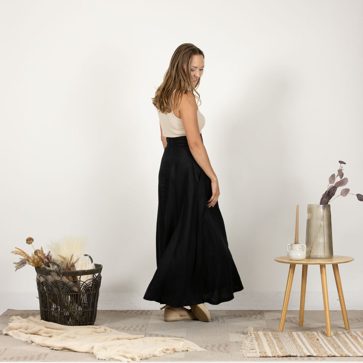 Side view of the Black Minimalist High Waist Linen Maxi Skirt, showcasing the smooth drape of the Italian linen fabric and the flattering high waist silhouette.